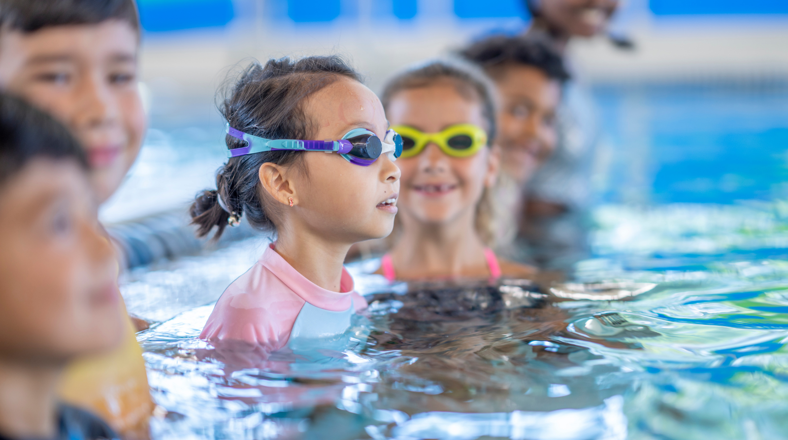 Mixed group of kids in a swimming lesson listen to the teacher Mixed group of kids in a swimming lesson listen to the teacher