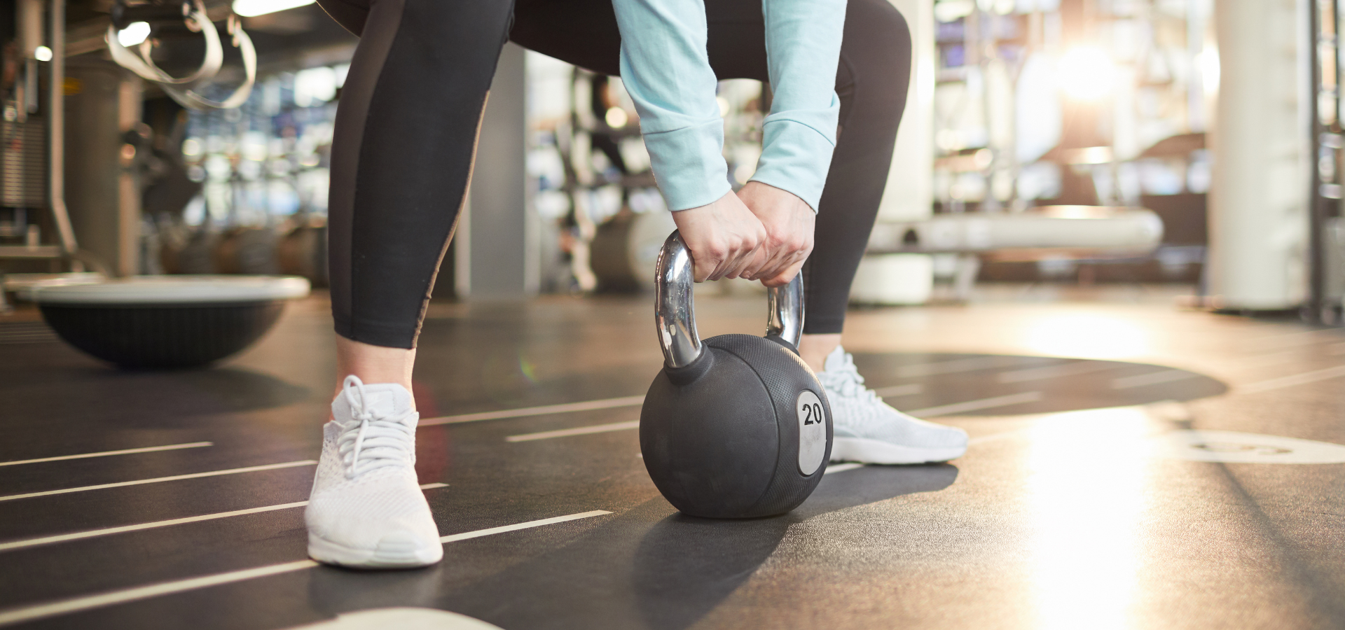 Woman lifts a kettlebell in a squatting position Woman lifts a kettlebell in a squatting position