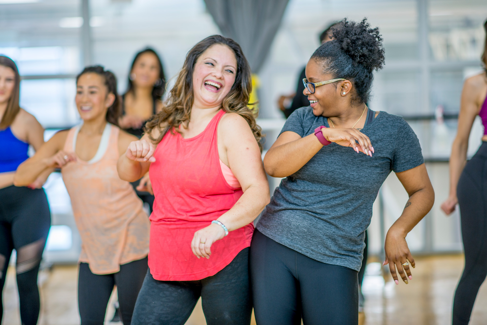 Two ladies laughing and taking part in a group fitness class Two ladies laughing and taking part in a group fitness class