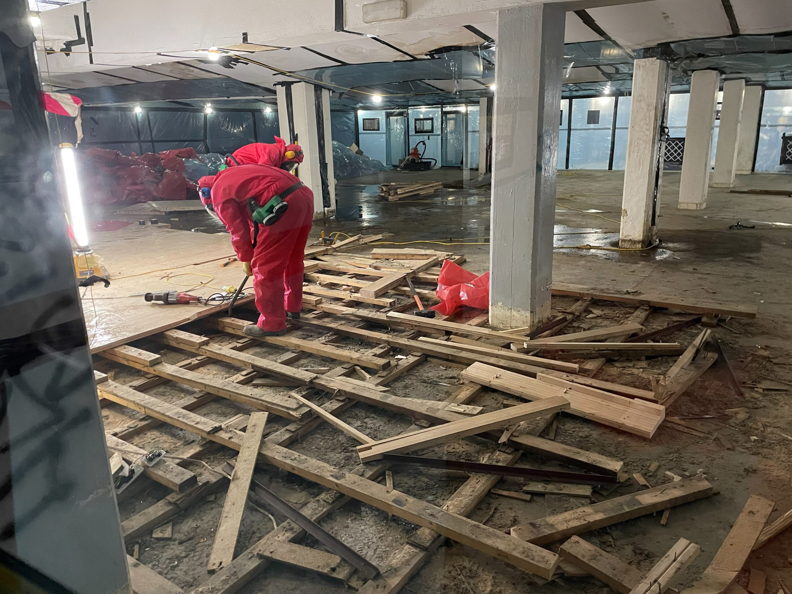 people in safety suits undertaking asbestos removal of disused bowling alley